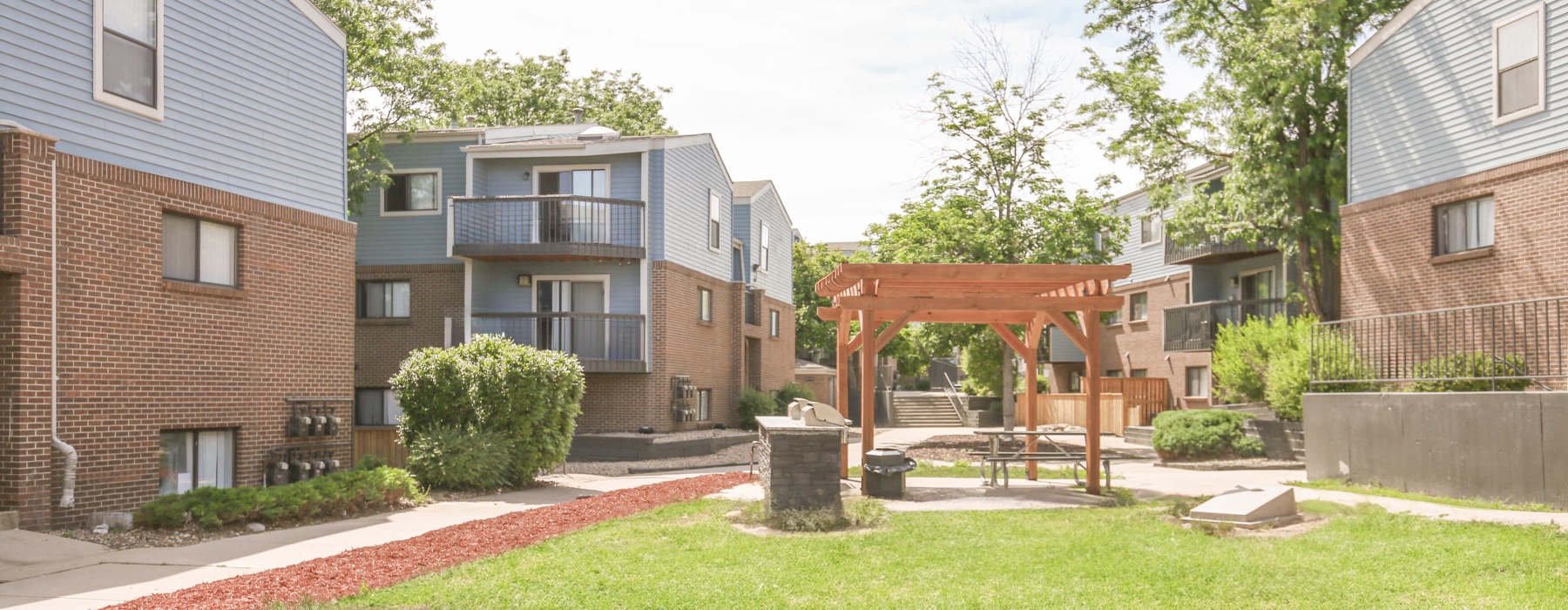 Cornhole area next to grilling area surrounded by buildings